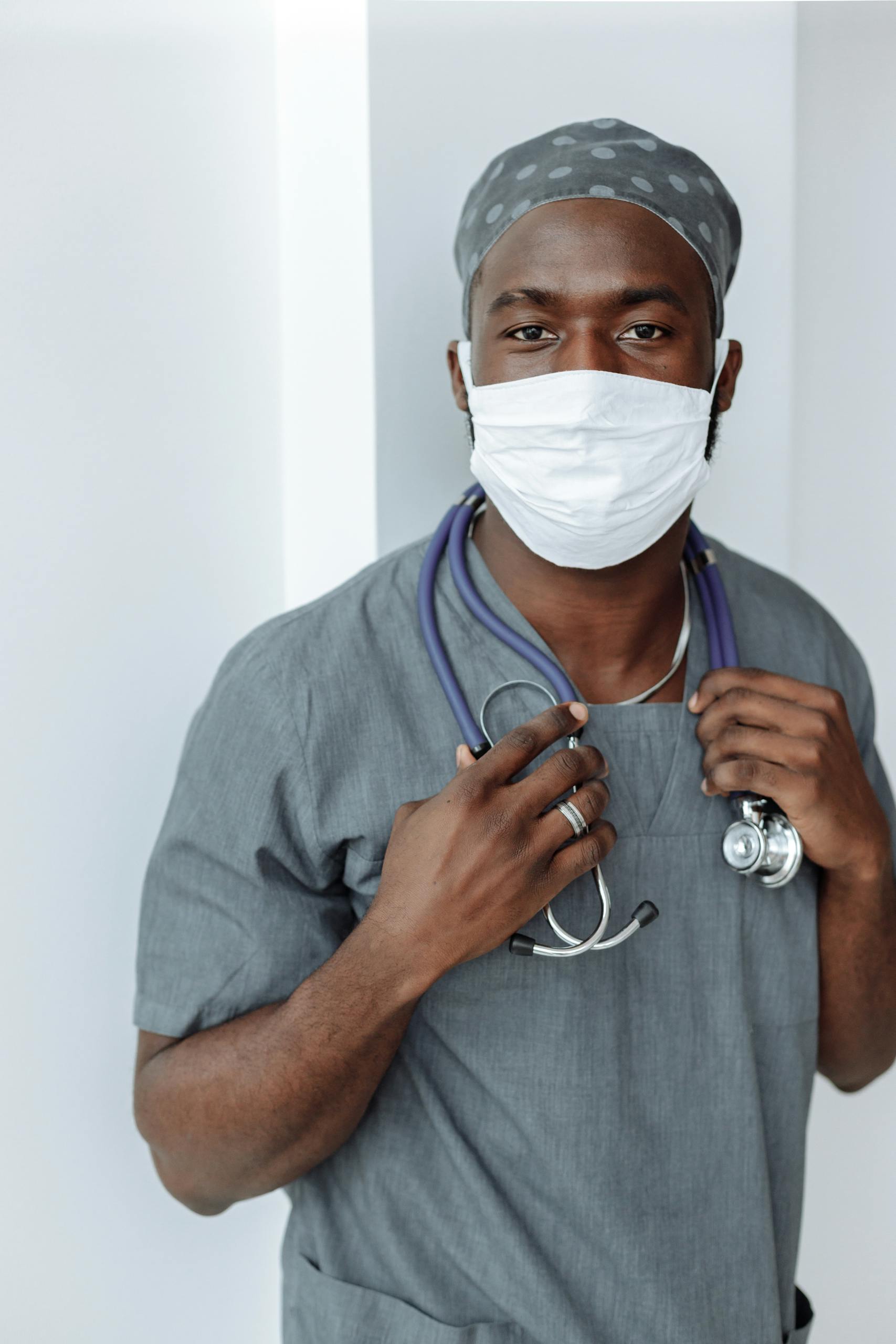 Portrait of a healthcare worker wearing a face mask and scrubs, demonstrating COVID-19 safety measures.